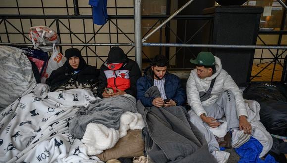 Migrantes acampan frente a un hotel donde habían estado alojados anteriormente, mientras se resisten a los esfuerzos de la ciudad para reubicarlos en un centro de Brooklyn para solicitantes de asilo, en el barrio Hells Kitchen de Nueva York el 31 de enero de 2023. (Foto de Ed JONES / AFP)