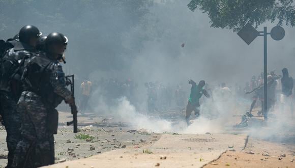 Partidarios del líder de la oposición, Ousmane Sonko, arrojan piedras mientras la policía dispara gases lacrimógenos en Dakar el 1 de junio de 2023. (Foto de GUY PETERSON / AFP)