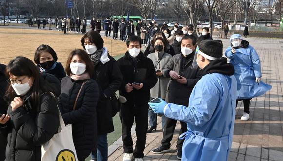 Los trabajadores de la salud que usan equipo de protección guían a las personas que esperan en la fila para hacerse las pruebas de coronavirus en Seúl, Corea del Sur, el 26 de enero de 2022. (Jung Yeon-je / AFP).