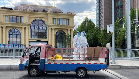 Trabajadores con trajes protectores se paran en un camión en una calle en medio del brote de la enfermedad por coronavirus (COVID-19), durante el feriado del Día del Trabajo, en el distrito de Chaoyang de Beijing, China.