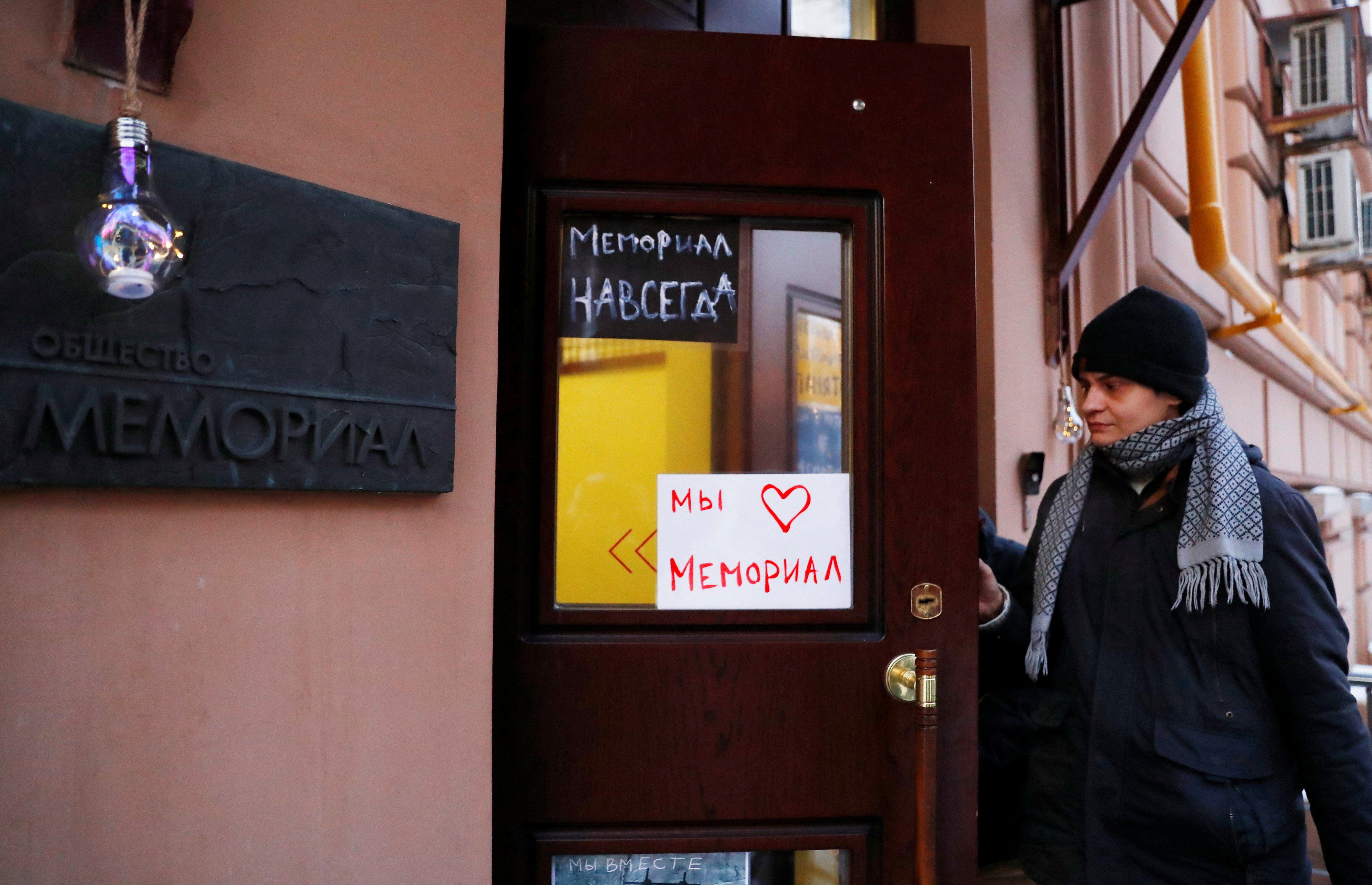 A man walks into an office of the human rights group Memorial in Moscow.  The banners read: 