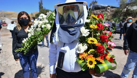 Habitantes de la comunidad rural de Yura, cercana a la ciudad de Arequipa, en el sur de Perú, participan en el entierro de su alcalde Angel Benavente, con una misa al aire libre y una posesión fúnebre. La autoridad murió de coronavirus. (Foto: Diego Ramos / AFP).