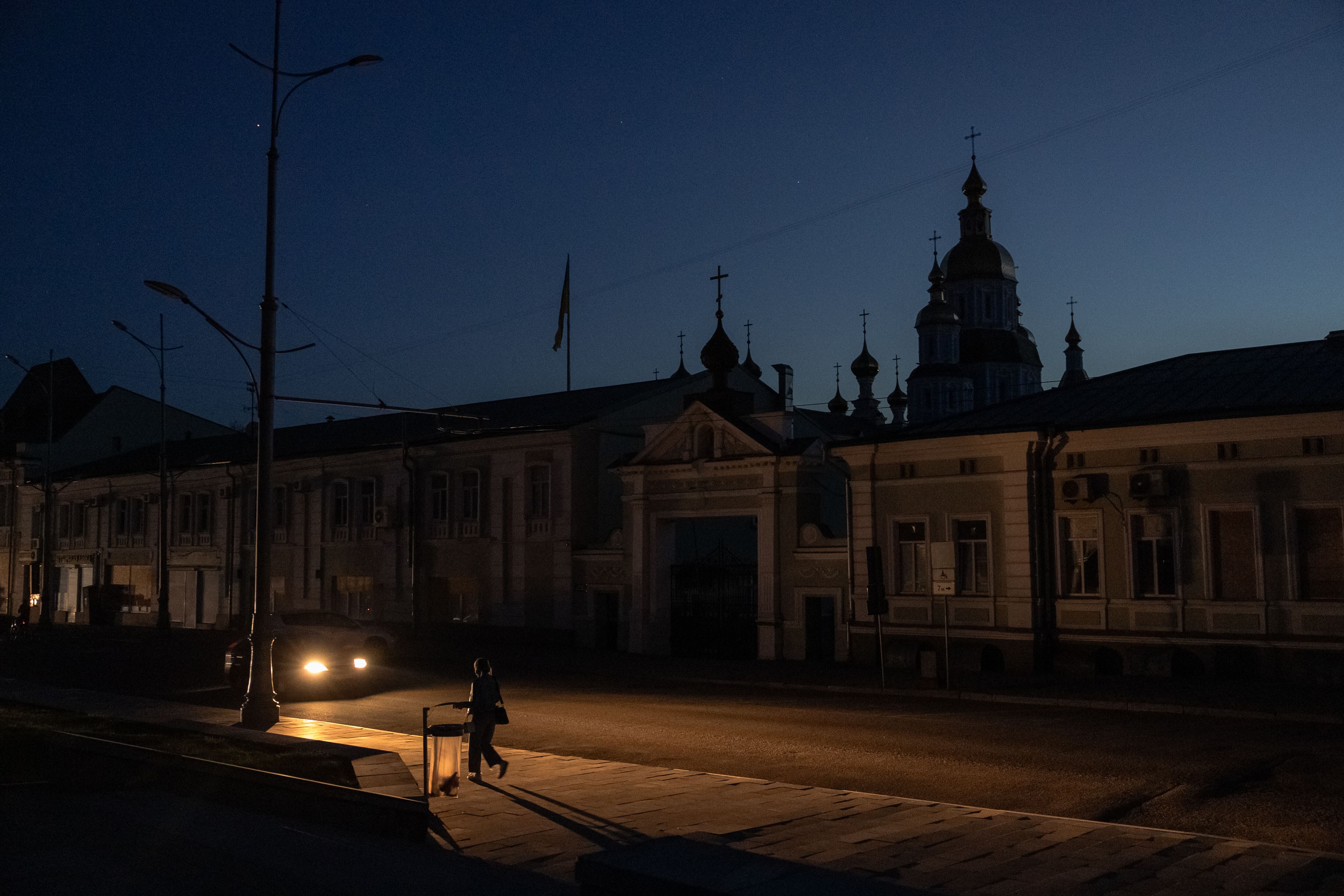 A person walks down a street during a blackout following Russian attacks on energy infrastructure in Kharkiv, April 8, 2024. (Photo by Román PILIPEY/AFP).
