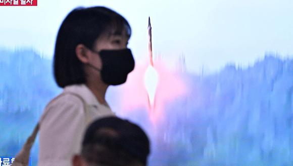 Una mujer pasa frente a un televisor que muestra una transmisión de noticias con imágenes de archivo de una prueba de misiles de Corea del Norte, en una estación de tren en Seúl el 15 de junio de 2023 (Foto: Anthony WALLACE / AFP)
