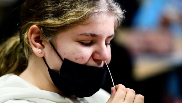 Una alumna toma una muestra para una prueba rápida de coronavirus en la escuela secundaria Freiherr-vom-Stein en Bonn, Alemania occidental, el 10 de enero de 2022. (INA FASSBENDER / AFP).