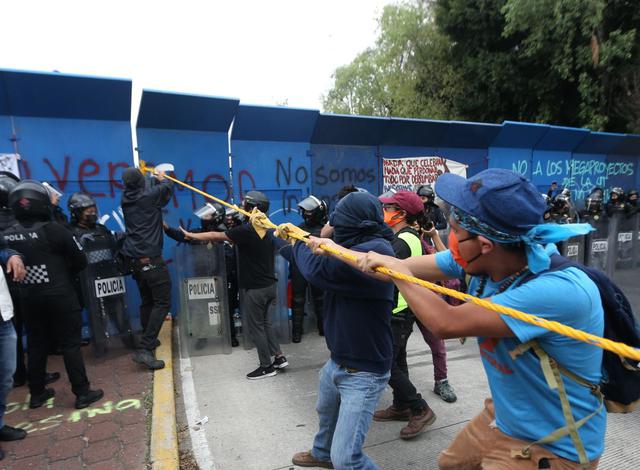 Manifestantes intentan derribar las barreras de acero que cercan el lugar en el que se ubica una estatua de Cristóbal Colón, en Ciudad de México. (EFE/Sáshenka Gutiérrez).