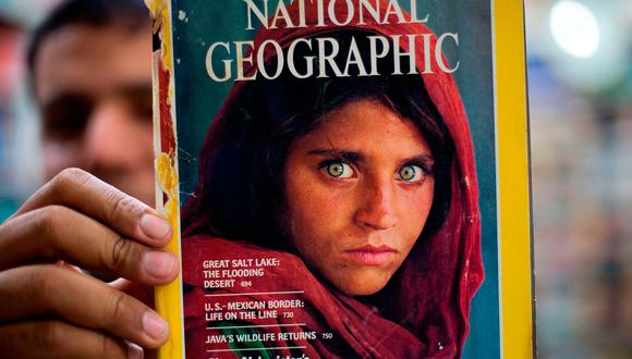 El propietario de una librería en Islamabad, Pakistán, muestra una de las portadas más famosas de la historia de National Geographic en la que aparece Sharbat Gula cuando era joven. (Foto: AP).