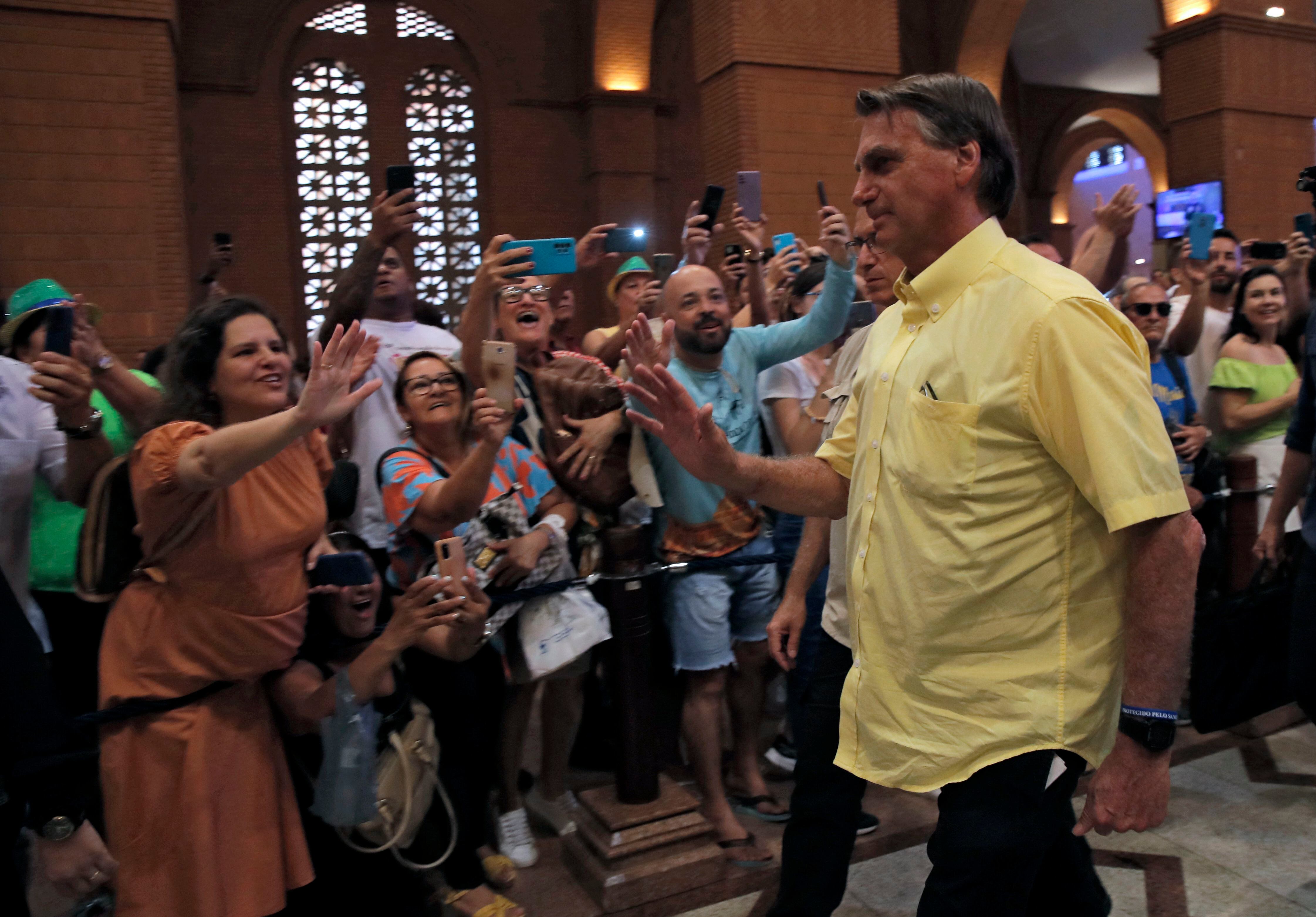 Brazilian President and re-election candidate Jair Bolsonaro is greeted by supporters as he arrives for a mass at the Basilica Cathedral of the National Shrine of Our Lady of Aparecida on Brazil's patron saint's day, in Aparecida, Sao Paulo state, in October.  January 12, 2022. (Photo by Caio GUATELLI / AFP)