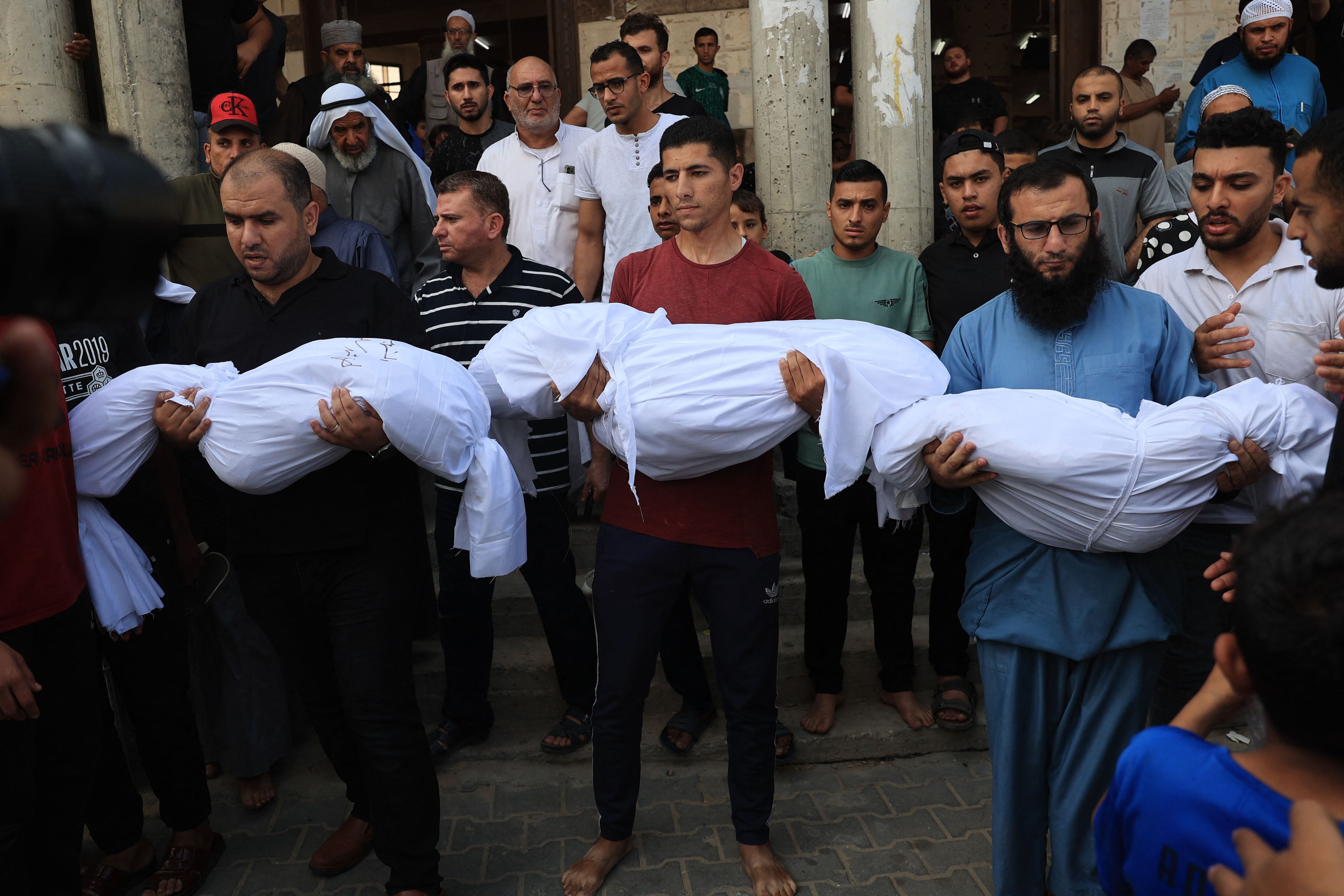 Familiares llevan los cuerpos de los niños de la familia Abu Quta que murieron en los ataques israelíes contra la ciudad palestina de Rafah, durante su funeral el 8 de octubre de 2023. (Foto de SAID KHATIB / AFP).