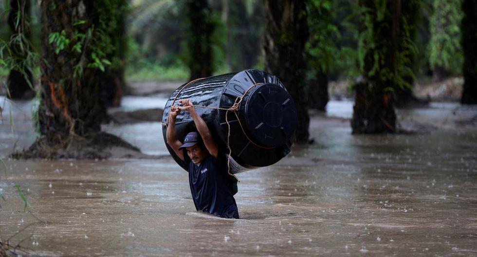 Un hombre lleva un tanque de agua vacío a través de un área inundada tras el impacto de la tormenta tropical Julia en Progreso, Honduras, 9 de octubre de 2022. (REUTERS/Yoseph Amaya).