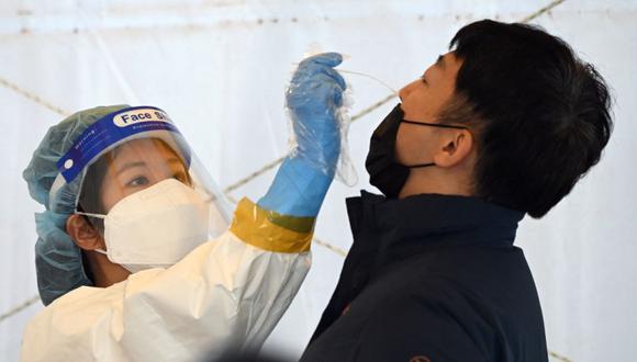 Un personal médico toma un hisopo nasal de un visitante como parte de una prueba del coronavirus Covid-19 en un centro de pruebas de virus en Seúl. (Foto: Jung Yeon-je / AFP)