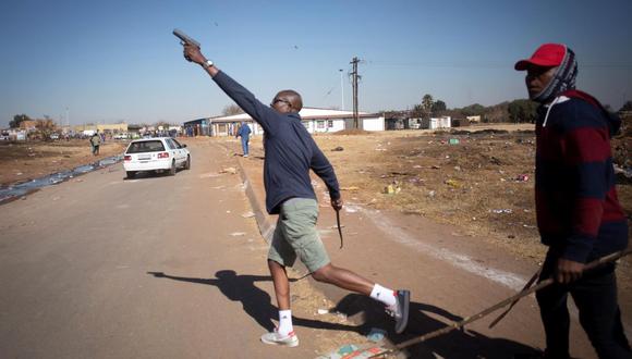 Un taxista dispara su pistola de 9 mm al aire para expulsar a los saqueadores cercanos de un centro comercial de Johannesburgo, Sudáfrica, el 14 de julio de 2021. (EFE / EPA / KIM LUDBROOK).