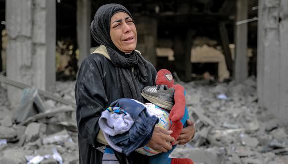 Una mujer palestina reacciona mientras sostiene sus pertenencias junto a los escombros de un edificio, después de que fuera destruido en un ataque israelí la noche anterior, en el barrio Rimal de la ciudad de Gaza el 16 de marzo de 2024, en medio de las batallas en curso entre Israel y los palestinos. (Foto de AFP)