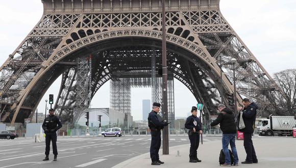 La policía pide los documentos un hombre que camina cerca de la torre Eiffel. Francia ya registra más de 500 muertos por coronavirus. (AFP / Ludovic MARIN).