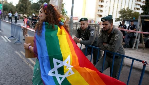 Una mujer marcha con una bandera de la comunidad LGBTI y la estrella de David en ella. (Foto de AFP)