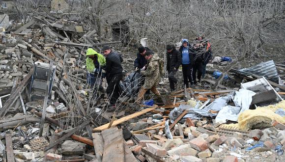 Expertos policiales y residentes locales llevan un cuerpo no identificado luego de un ataque ruso en la aldea de Velyka Vilshanytsia, a unos 50 km de Lviv, el 9 de marzo de 2023 (Foto: YURIY DYACHYSHYN / AFP)