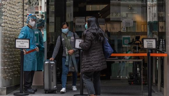 Una mujer sale de un hotel de cuarentena en el área central de Hong Kong el 6 de febrero de 2022, cuando las autoridades anunciaron el 5 de febrero un número récord de nuevas infecciones. (Foto de Bertha WANG / AFP)