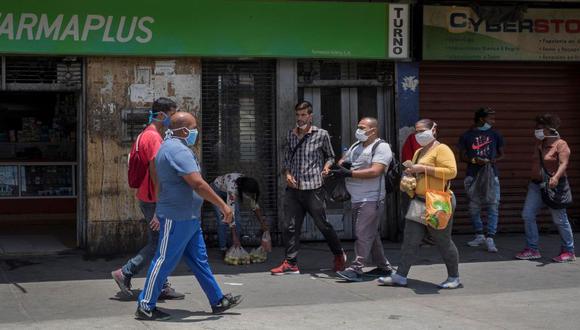Personas con tapabocas caminan el pasado frente a una farmacia de Caracas (Venezuela). (Foto: EFE).
