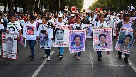 Imagen de archivo | Familiares de las víctimas de Ayotzinapa sostienen carteles durante una marcha para conmemorar el noveno aniversario de la desaparición de los 43 estudiantes de la escuela de formación docente de Ayotzinapa, en la Ciudad de México. (Foto de ALFREDO ESTRELLA/AFP)