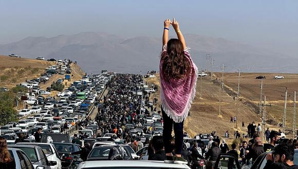 Esta imagen UGC publicada en Twitter supuestamente el 26 de octubre de 2022 muestra a una mujer sin velo de pie sobre un vehículo mientras miles se dirigen hacia el cementerio de Aichi en Saqez, la ciudad natal de Mahsa Amini en la provincia occidental iraní de Kurdistán, para marcar 40 días desde su muerte, desafiando las estrictas medidas de seguridad como parte de una sangrienta represión de las protestas lideradas por mujeres. (Foto: UGC / AFP)