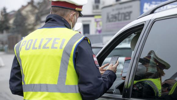 Un policía austriaco verifica el certificado de vacunación contra el coronavirus de un conductor en un teléfono inteligente durante un control de tráfico en Graz, Austria, el 15 de noviembre de 2021. (ERWIN SCHERIAU / APA / AFP).