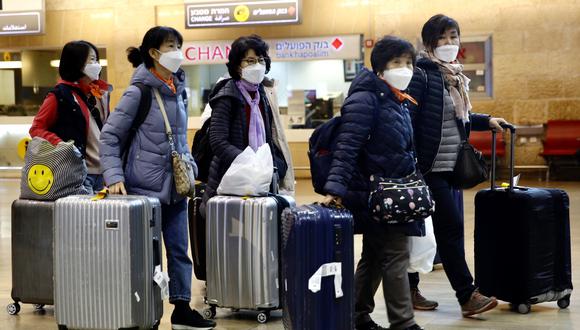 Turistas de Corea del Sur con máscaras protectoras para tratar de evitar el contagio del coronavirus se desplazan en el aeropuerto Ben Gurion, cerca de Tel Aviv, Israel. (Foto AP / Ariel Schalit).