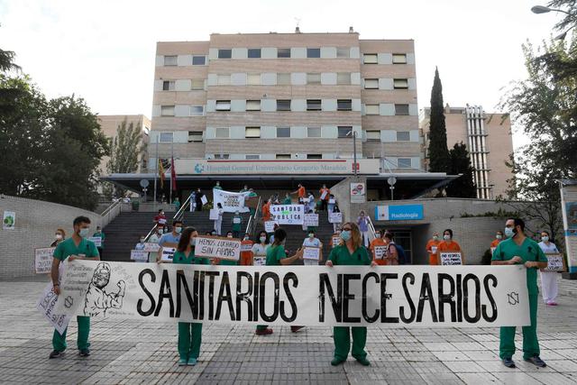 Enfundados en sus uniformes verdes y blancos, trabajadores del sistema sanitario se manifestaron este lunes frente a varios hospitales en Madrid para exigir más medios en la región, la más golpeada por el coronavirus en España. (AFP / PIERRE-PHILIPPE MARCOU).