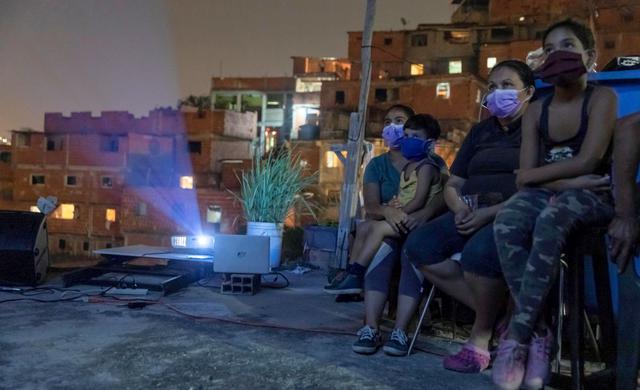 Residentes observan una película desde el techo de una vivienda en el barrio José Félix Ribas, en Petare, Caracas (Venezuela). (Foto: EFE/Rayner Pena R).