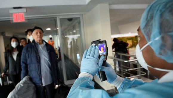 Un trabajador del Ministerio de Salud de Ecuador utiliza un escáner térmico para examinar a los pasajeros que llegan de los EE. UU. (Foto: Reuters).