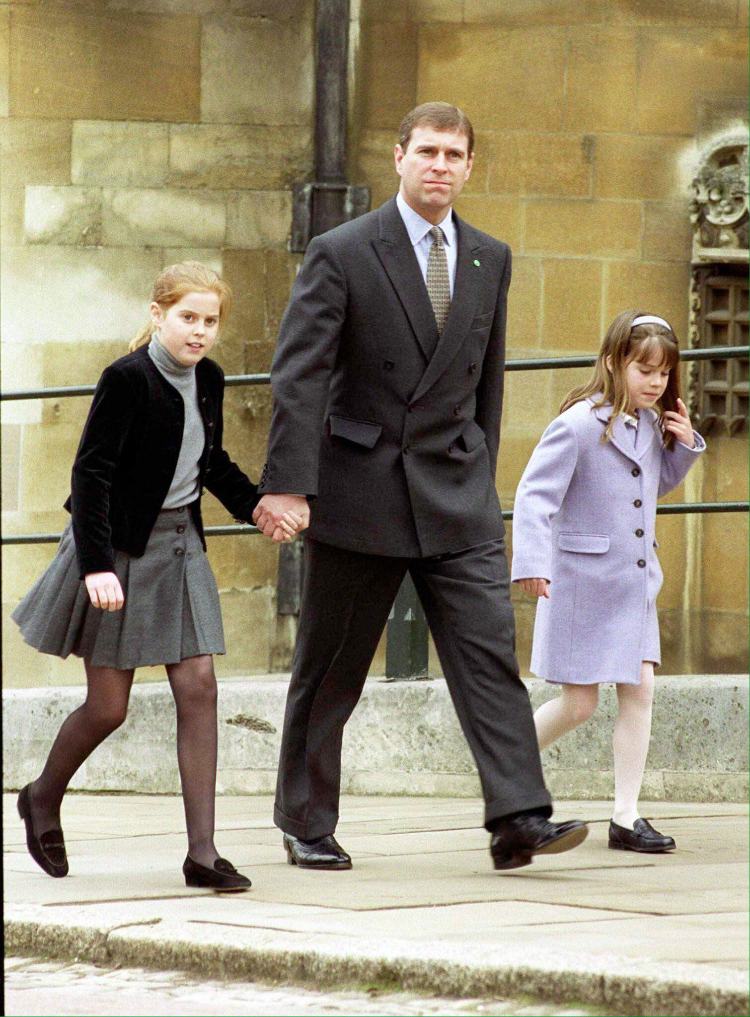 Andrés de York junto a sus hijas, las princesas Beatriz (izquierda) y Eugenia (derecha) afuera de la Catedral de San Jorge, en Londres, en abril de 1999. (AFP)