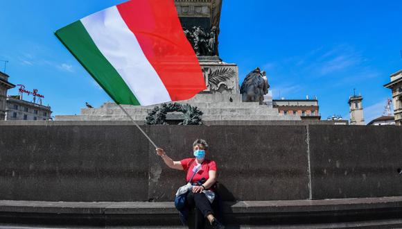Una mujer ondea la bandera de Italia en Milán. El país ha controlado la pandemia de coronavirus. (Foto: Miguel MEDINA / AFP).