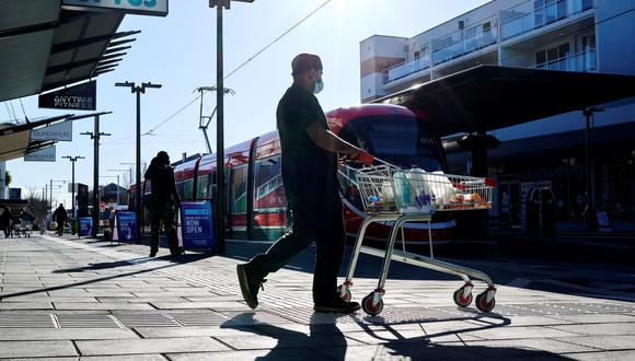 Un hombre sale de un supermercado en Canberra el 12 de agosto de 2021, tras la orden de confinamiento por coronavirus decretada por el gobierno de Australia. (Foto de Rohan THOMSON / AFP).