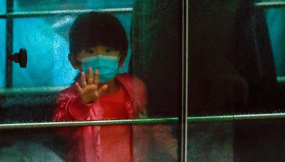 Una niña saluda mientras se sienta en un vehículo que transporta a los residentes que fueron evacuados de un edificio de de Hong Kong después de que se detectara a dos sospechosos de haberse contagiado con el coronavirus. (REUTERS / Tyrone Siu).