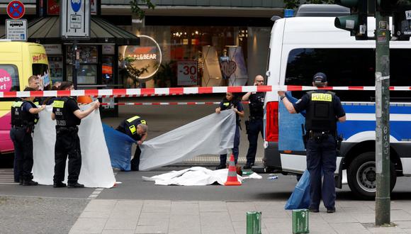 La policía cubre el cuerpo de una víctima en el sitio de un atropello masivo en el centro de Berlín, Alemania, el 8 de junio de 2022. (Odd ANDERSEN / AFP).