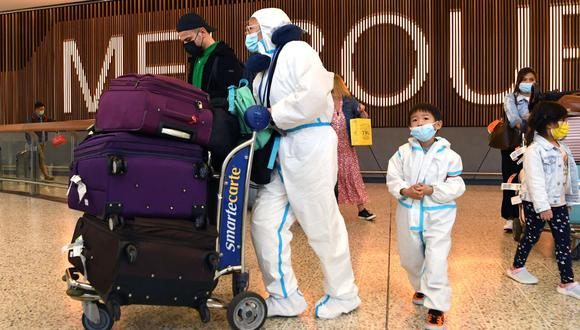 Los viajeros internacionales que usan equipo de protección personal (PPE) llegan al aeropuerto Tullamarine de Melbourne, el 29 de noviembre de 2021, cuando Australia registra sus primeros casos de la variante Omicron del coronavirus. (William WEST / AFP).