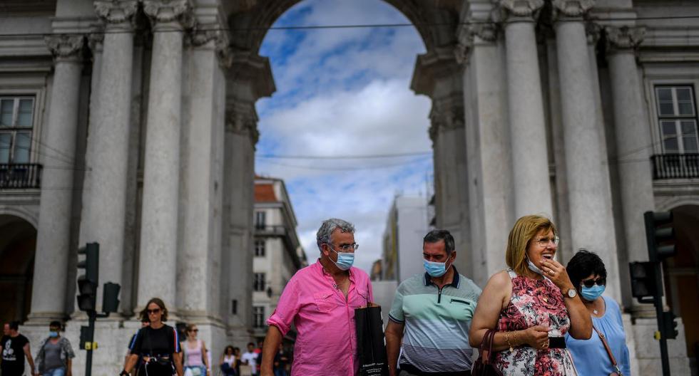 Personas cruzan una calle frente al arco de la Rua Augusta en el centro de Lisboa el 13 de septiembre de 2021. Portugal eliminó la obligación de llevar mascarilla en las calles por el coronavirus. (PATRICIA DE MELO MOREIRA / AFP).