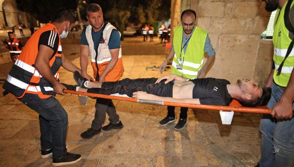 Médicos palestinos evacuan a un hombre herido durante los enfrentamientos entre las fuerzas de seguridad israelíes y manifestantes en el recinto de la mezquita de al-Aqsa en Jerusalén . (Foto de Ahmad GHARABLI / AFP).