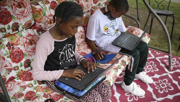 En esta imagen del 5 de junio de 2020 Sammiayah Thompson, estudiante de cuarto grado, y su hermano Nehemiah Thompson, quien cursa el tercer grado, trabajan desde su jardín en laptops que les entregó su sistema escolar para el aprendizaje remoto en Hartford, Connecticut. (AP Foto/Jessica Hill, Archivo).