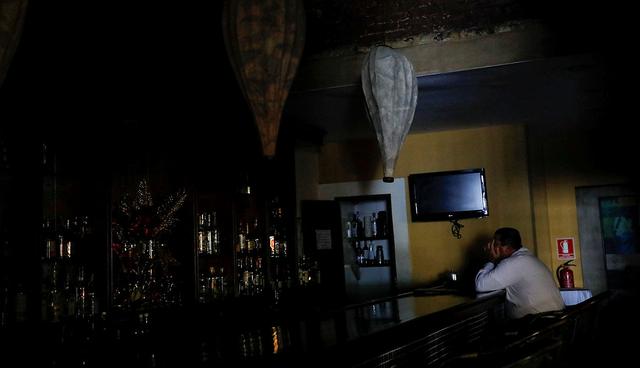 A worker waits for clients at the bar of a restaurant, during a massive blackout in Caracas, Venezuela December 18, 2017. REUTERS/Carlos Garcia Rawlins