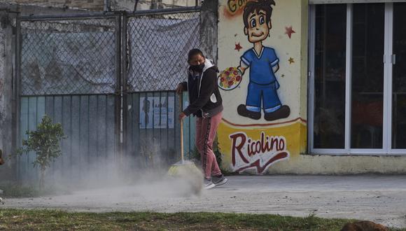 Una mujer barre la ceniza arrojada por el volcán Popocatépetl, en la comunidad de Santiago Xalitzintla, estado de Puebla, México, el 24 de mayo de 2023. (Foto por CLAUDIO CRUZ / AFP)