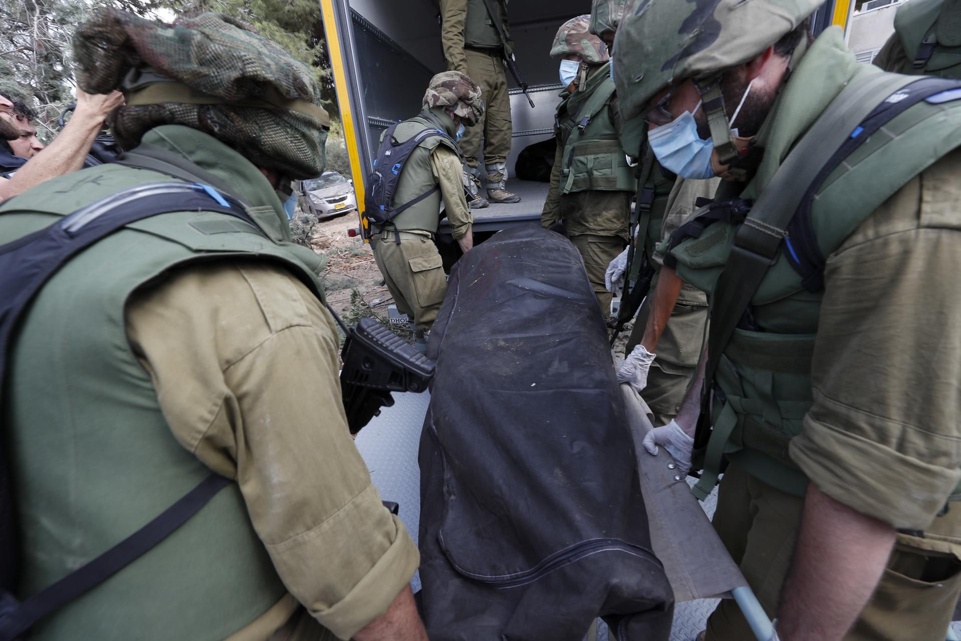Israeli soldiers carry bodies of murdered Israelis in kibbutz Kfar Aza, near the border with Gaza, on October 10, 2023. (EFE/EPA/ATEF SAFADI).