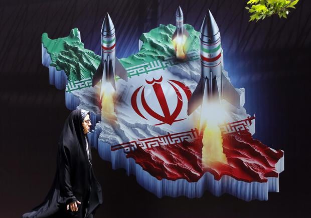 Una mujer iraní pasa junto a una pancarta antiisraelí con imágenes de misiles de Irán, en Teherán el 16 de abril de 2024. (EFE/ABEDIN TAHERKENAREH).