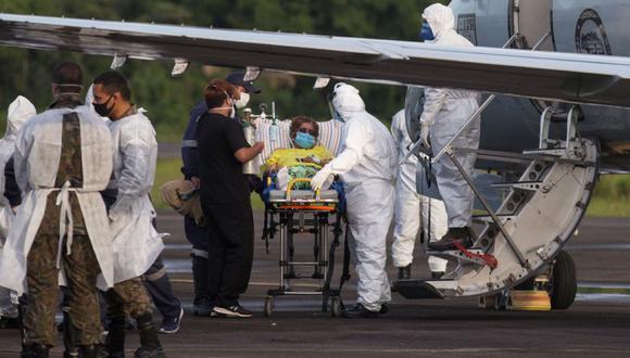 Un paciente de COVID-19, uno de los 12 que serán trasladados en un avión militar, es asistido por personal médico en el aeropuerto Ponta Pelada en Manaus, estado de Amazonas, Brasil en medio de la pandemia del nuevo coronavirus. (Foto: AFP / Michael DANTAS).