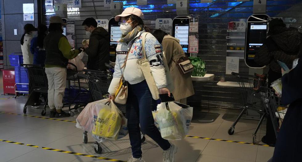 Una residente lleva sus compras cerca de los cajeros automáticos de un supermercado en Beijing, China, el viernes 25 de noviembre de 2022. (Foto AP/Ng Han Guan).
