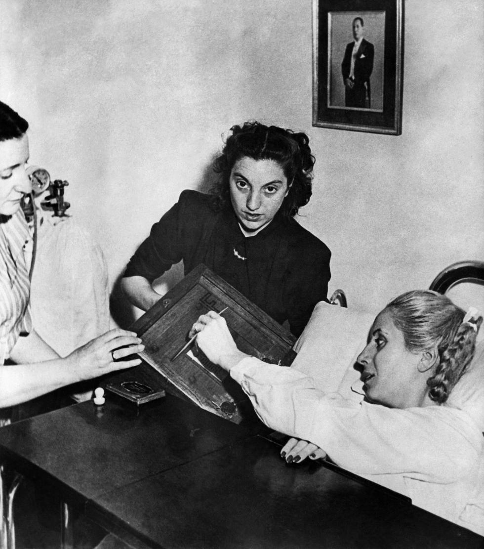 Un día como hoy más 3 millones de mujeres en Argentina, entre ellas Evita, votaron por primera vez en la elección presidencial que le daría su segundo gobierno a Juan Domingo Perón. Sería el primer y único voto que Eva Perón haría en su vida, pero quizás el más importante para todas las argentinas. En la fotografía tomada el 11 de noviembre de 1951 en Buenos Aires, se ve a Eva Perón (1919-52) emitiendo su voto desde la cama de un hospital. (Foto de INTERCONTINENTALE / AFP)