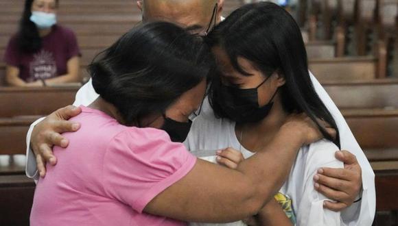 El sacerdote Flaviano "Flavie" Villanueva consola a familiares mientras recibe la urna que contiene los restos de víctimas de asesinatos extrajudiciales en una iglesia en la ciudad de Quezon, Filipinas.