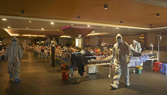 Los trabajadores de la salud que usan equipo de protección personal atienden a pacientes positivos de coronavirus Covid-19 dentro de un salón de banquetes convertido en un centro de atención de covid en Nueva Delhi, India. (Foto de TAUSEEF MUSTAFA / AFP).