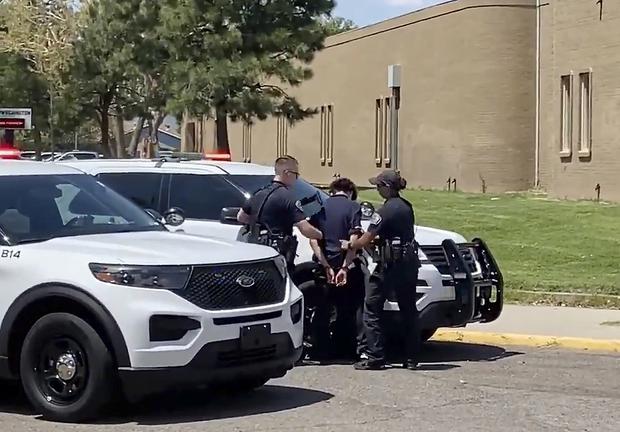 In this image taken from a video courtesy of Ryan Laughlin / KOB 4 TV, Albuquerque Police Department officers search a student after a shooting at Washington Middle School that left at least one student dead and another in custody.