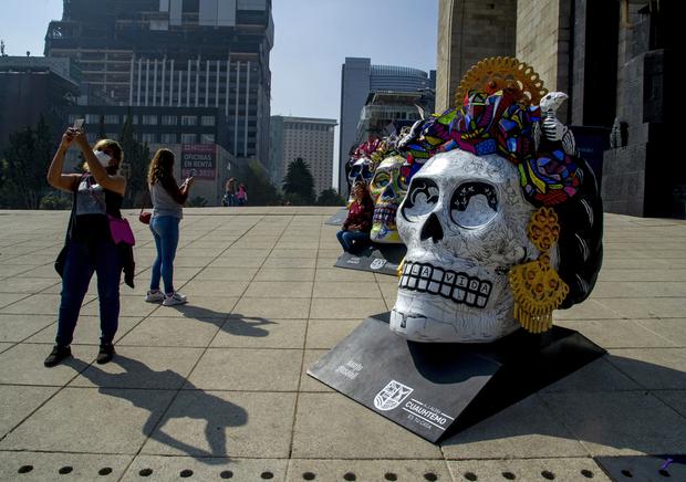 People take photos and selfies at the "Fridacraneos" exhibition, which consists of giant skulls painted in honor of the late Mexican artist Frida Kahlo and displayed as part of the Day of the Dead celebrations at the Monument to the Revolution in the City of Mexico.  (Photo: Claudio CRUZ / AFP)