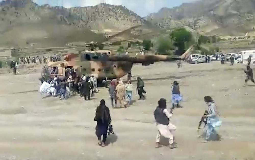 In this image taken from a video by the state-run Bakhtar news agency, Taliban fighters guard a helicopter carrying wounded in Gayan district, Paktika province, Afghanistan.  (State Bakhtar News Agency via AP)